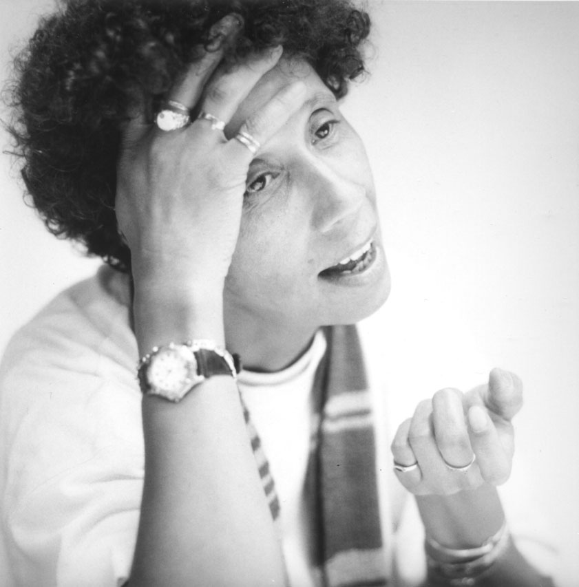 Black and white photo of Ika Hügel-Marshall leaning her head on her left hand and gesturing with her right hand.
